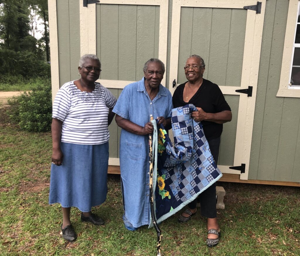 Elease Varner, Willie Bell Philyor, and Mary Beechim pose with a quilt.